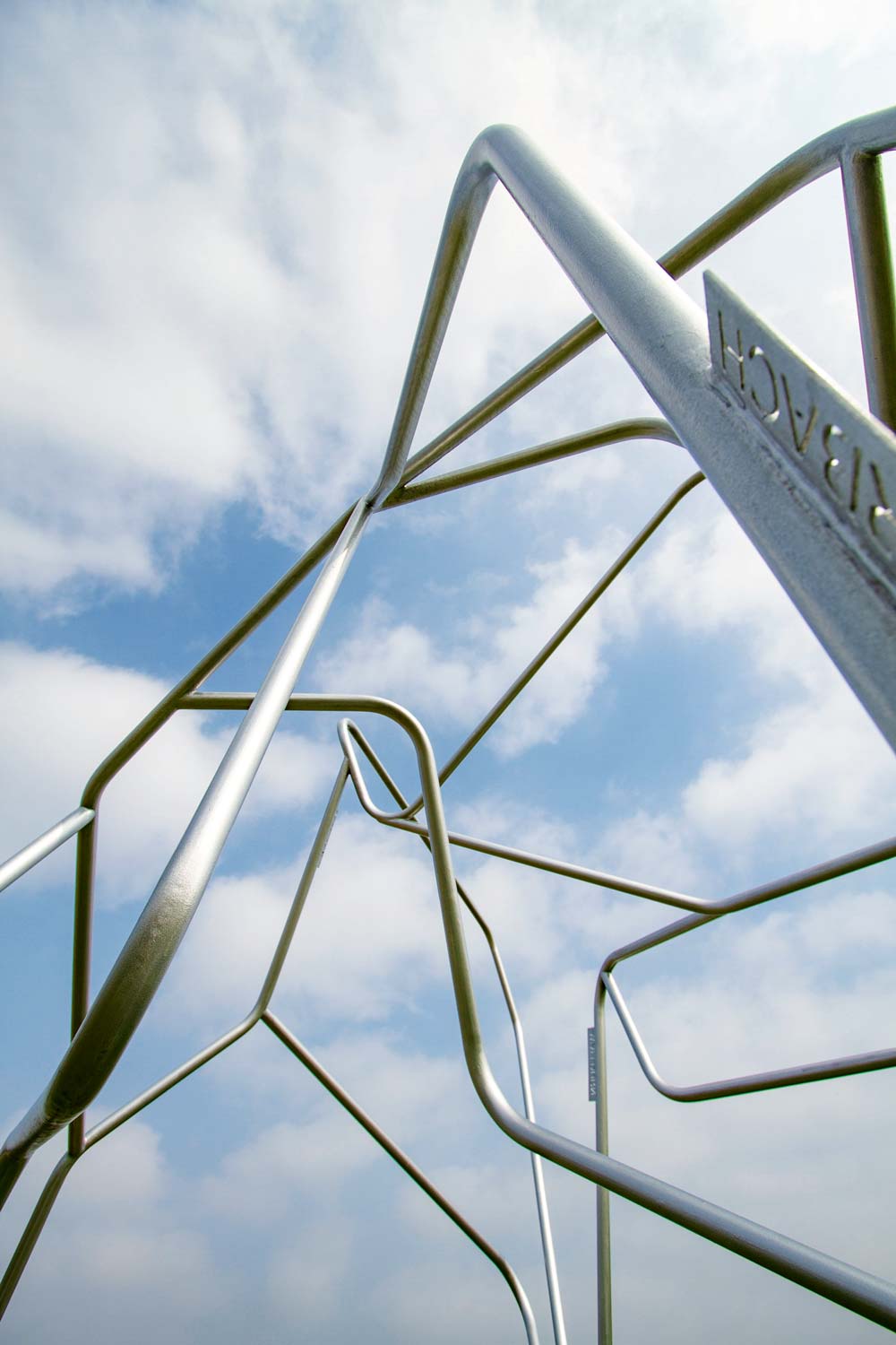 Stangen mit Ortsschildern als Skulptur verwurstelt