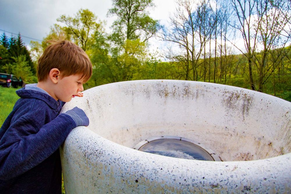 Kind guckt in die Skulptur
